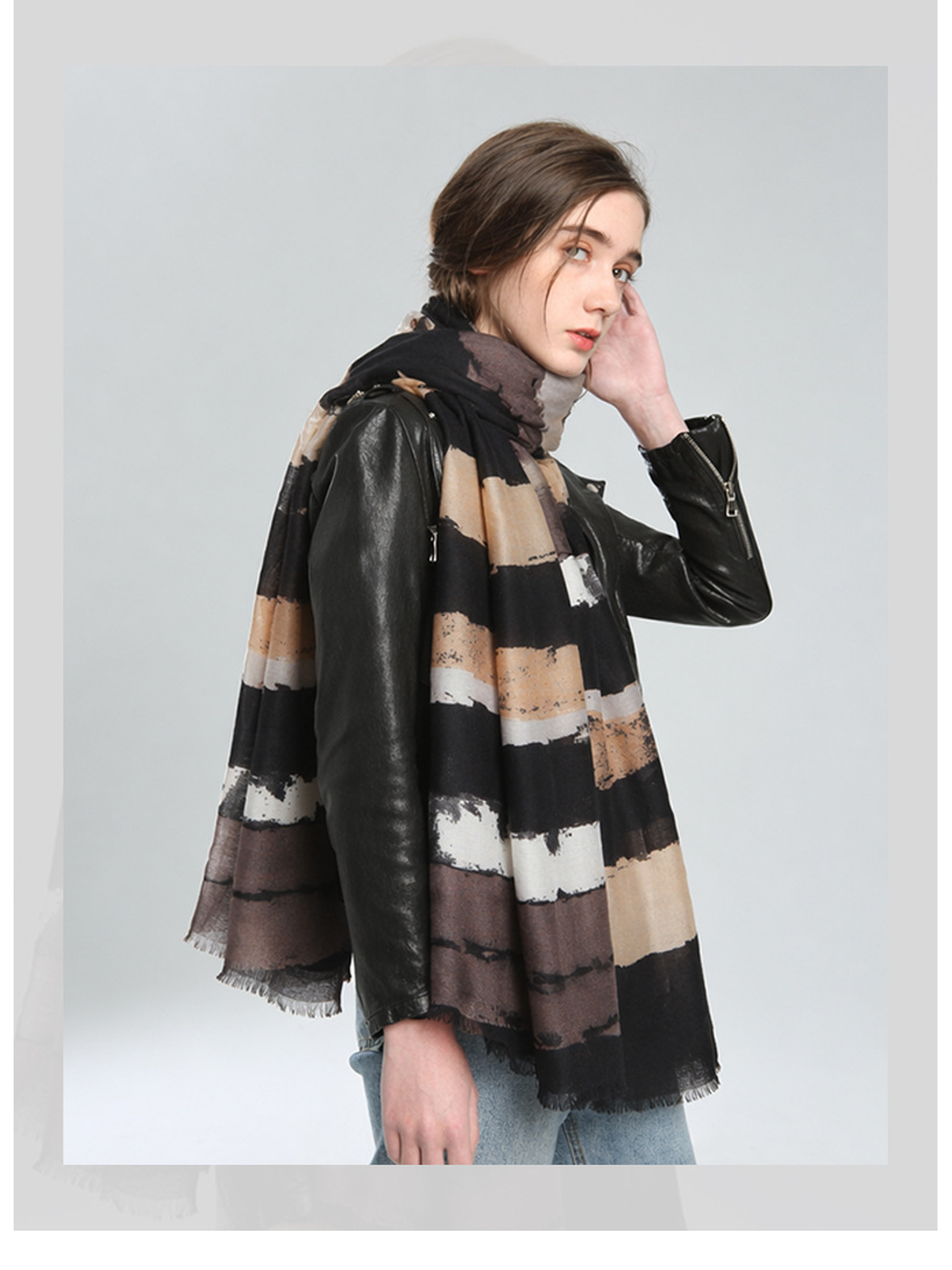 Black, beige and taupe striped scarf worn draped over a jacket