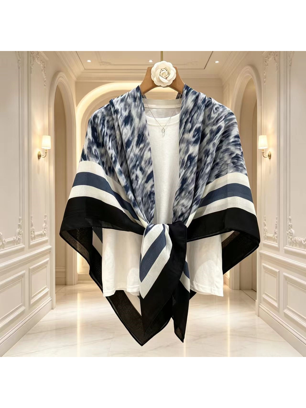 Blue-gray, black and white scarf draped over a white top and tied at the front