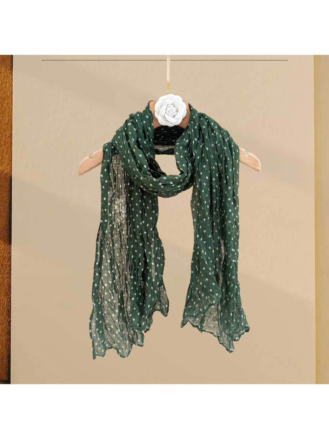 Dark green polka-dot scarf with floral accents, draped on a hanger