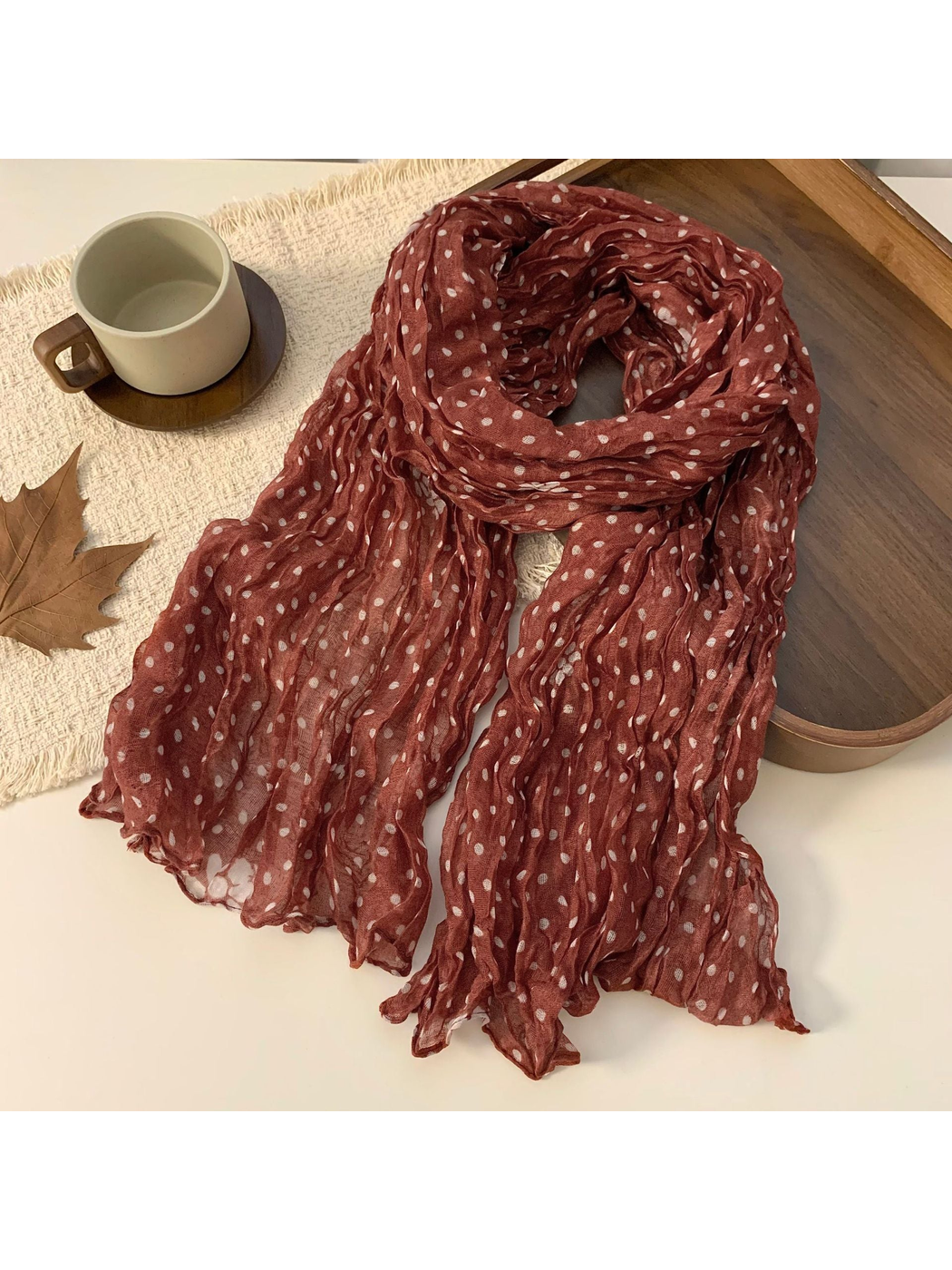 Orange-red polka-dot scarf loosely looped in a tabletop display