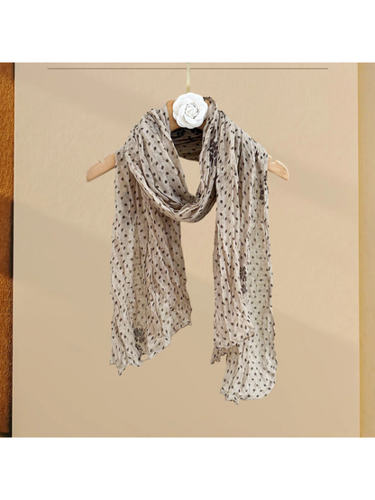 Beige polka-dot scarf with floral accents, draped on a hanger