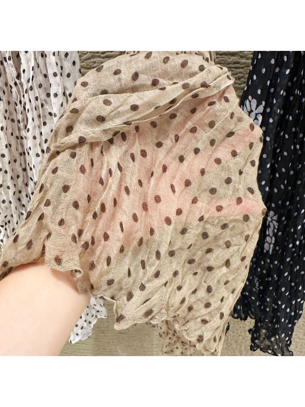 Close-up of the beige scarf's semi-sheer open weave and crinkled dotted surface