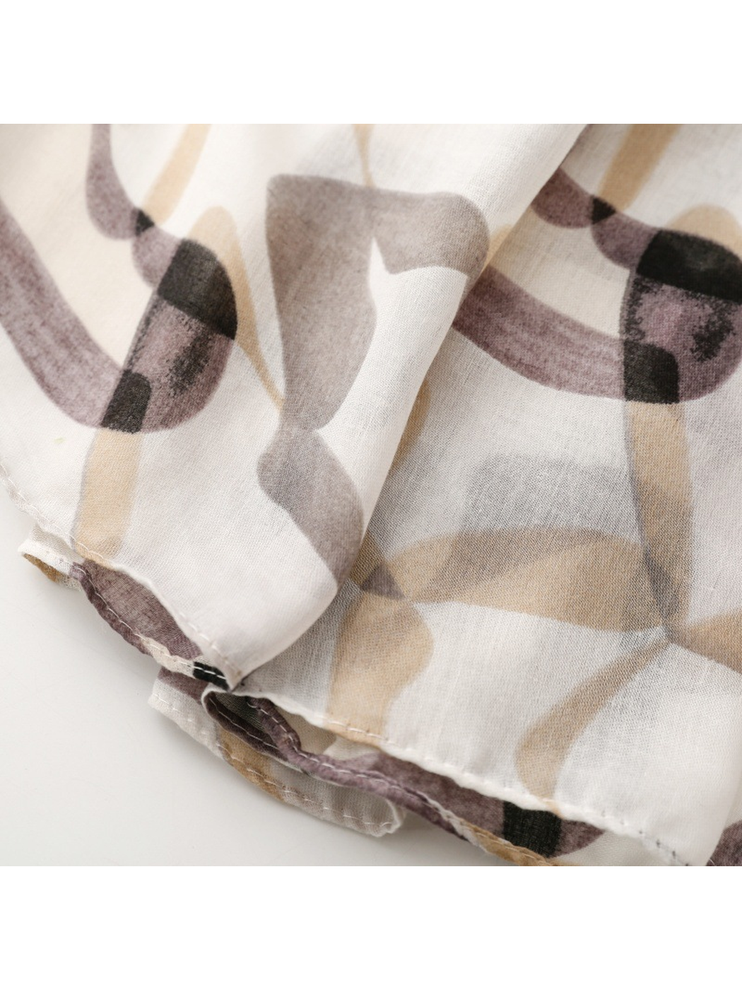 Close-up of the narrow stitched hem on the gray abstract-print scarf