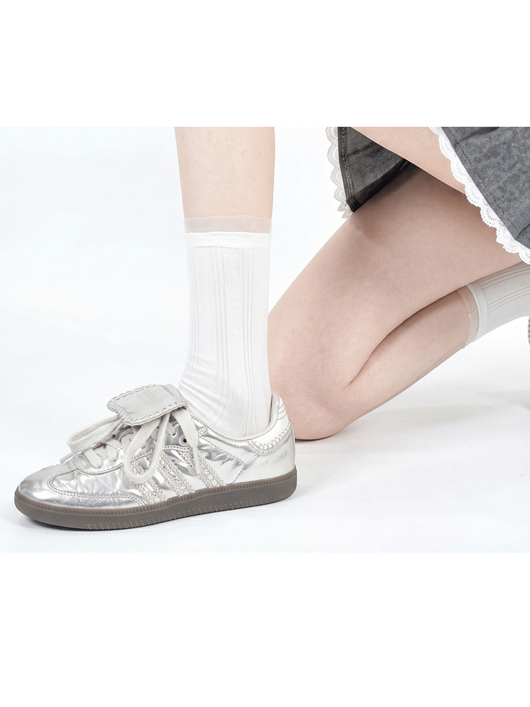 White sheer striped crew sock worn with a silver sneaker, side close-up