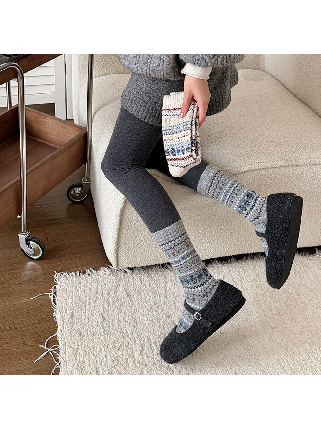 Gray patterned crew socks worn while holding the cream color option