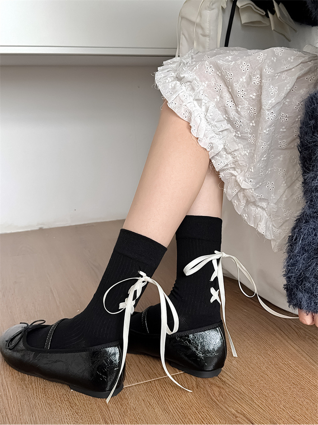 Side view of black ribbed socks with ivory ribbon ties worn with flats
