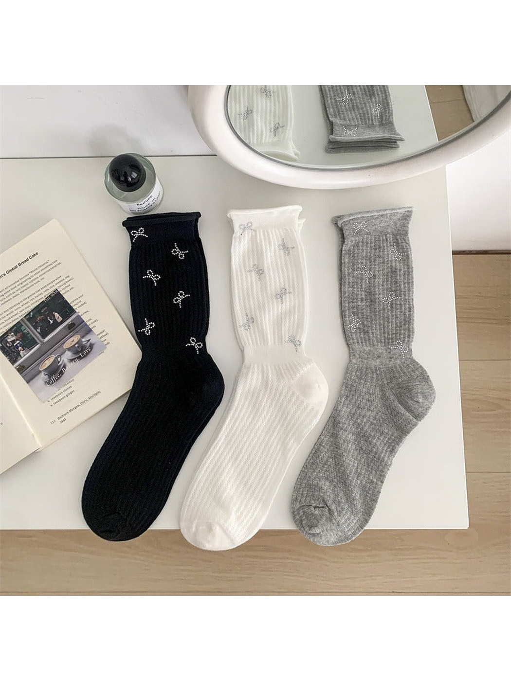 Black, white and heather gray bow-motif crew socks displayed together