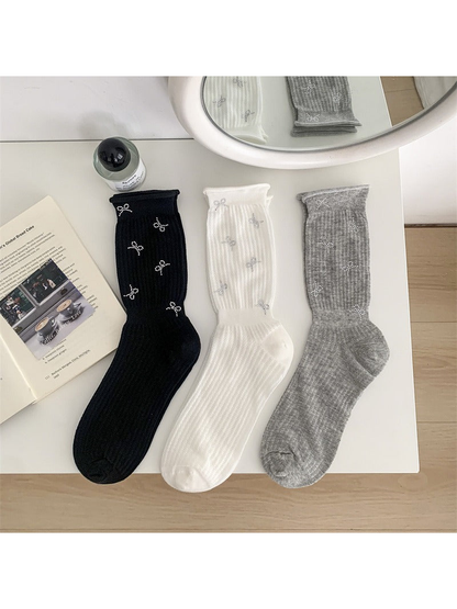 Black, white and heather gray bow-motif crew socks displayed together