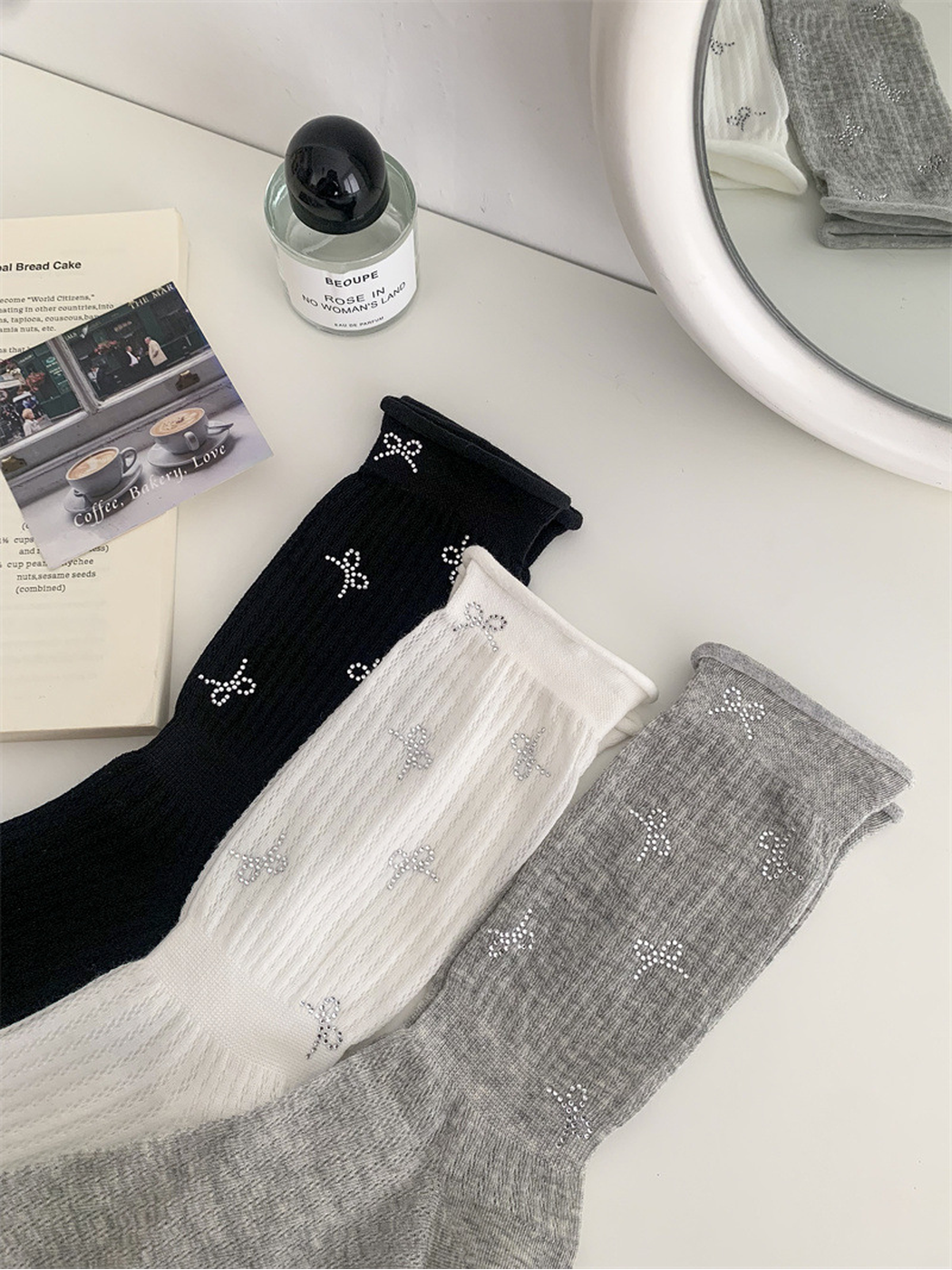 Close view of black, white and heather gray socks with silver-tone bow motifs