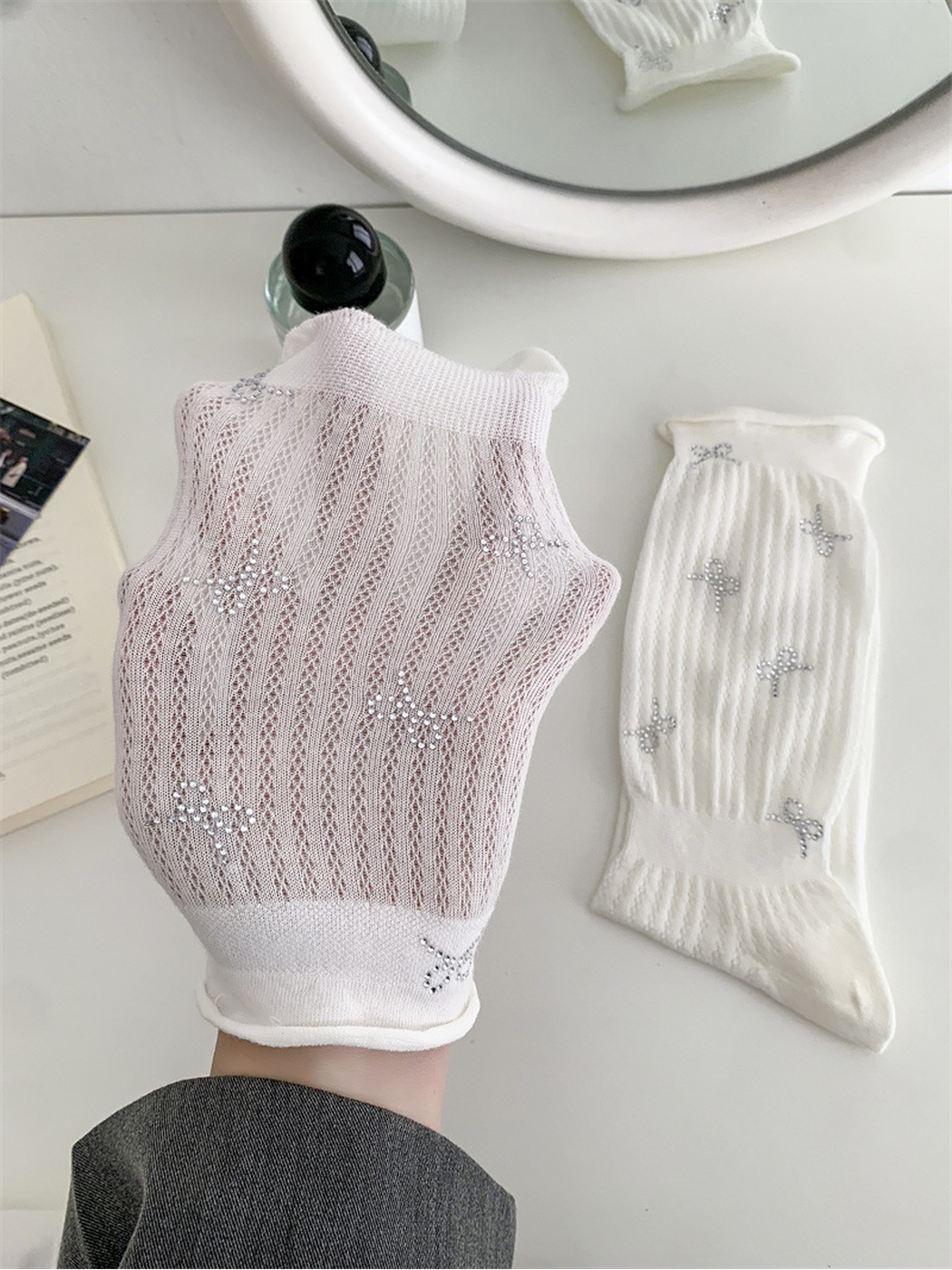 Close-up of the white sock's pointelle texture and silver-tone bow motifs