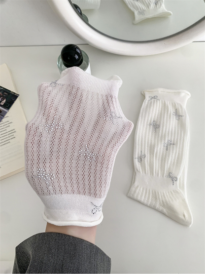 Close-up of the white sock's pointelle texture and silver-tone bow motifs