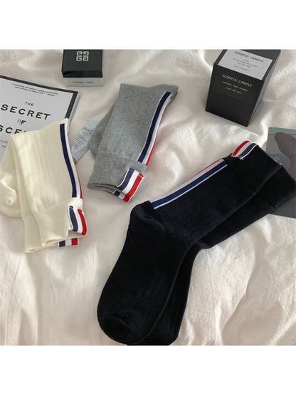 Black, ivory and gray striped crew socks in a folded flat lay