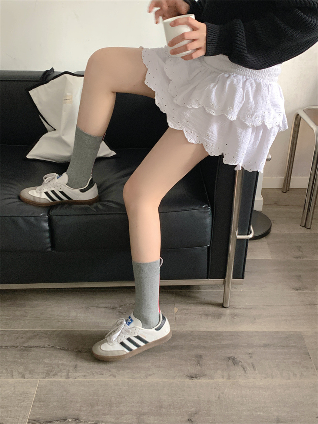 Gray crew socks worn with white sneakers in a seated pose