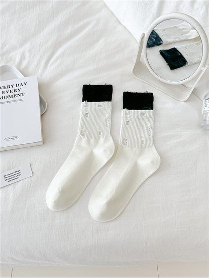 Ivory distressed crew socks with wide black cuffs, flat lay