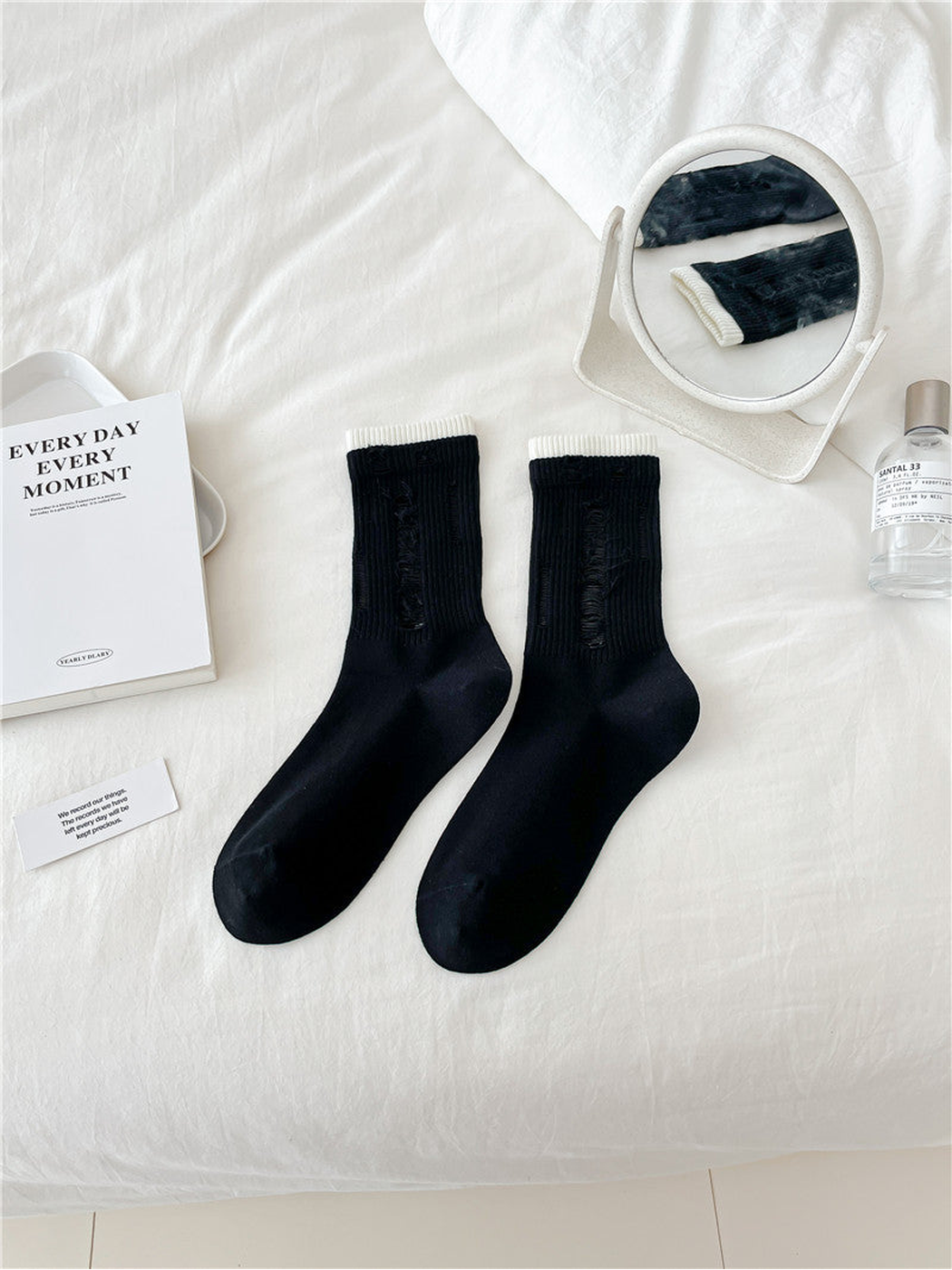 Black distressed crew socks with narrow ivory trim, flat lay