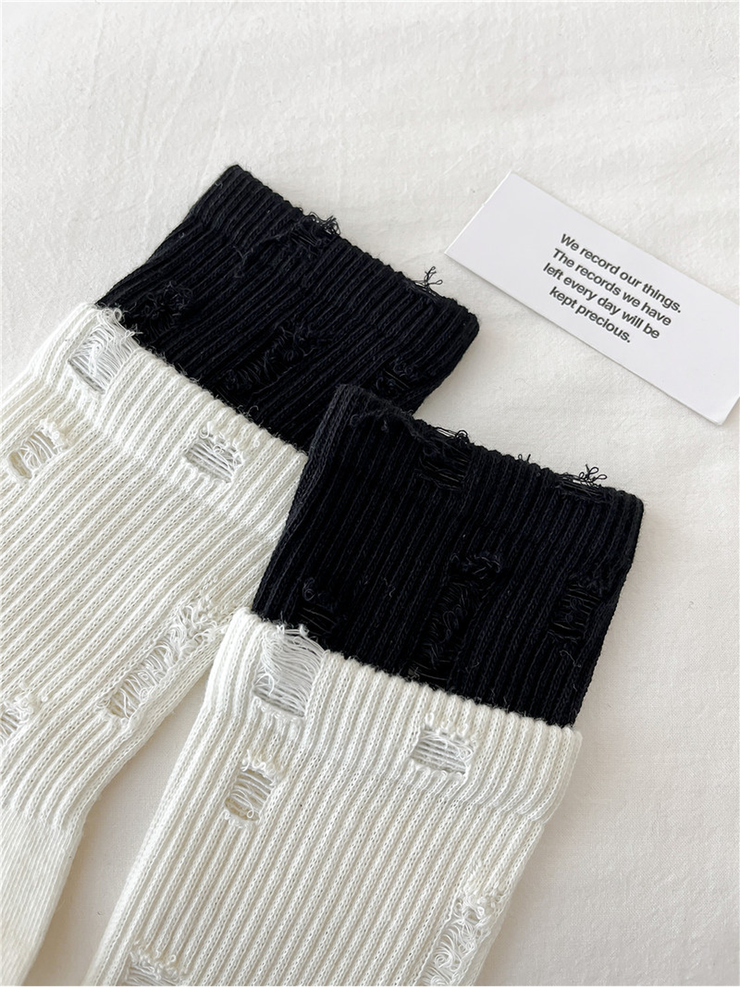 Close-up of distressed laddered openings across the ribbed sock legs