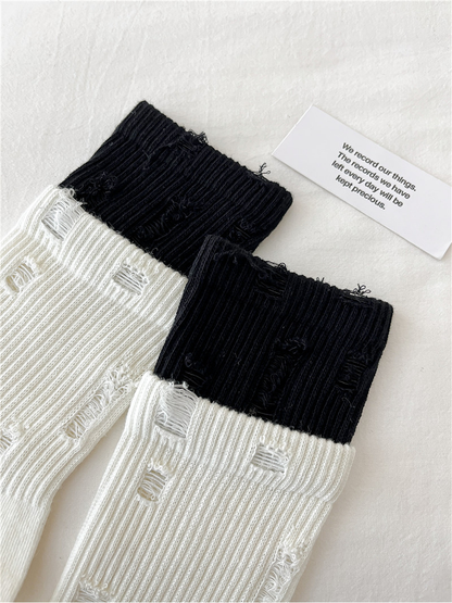 Close-up of distressed laddered openings across the ribbed sock legs