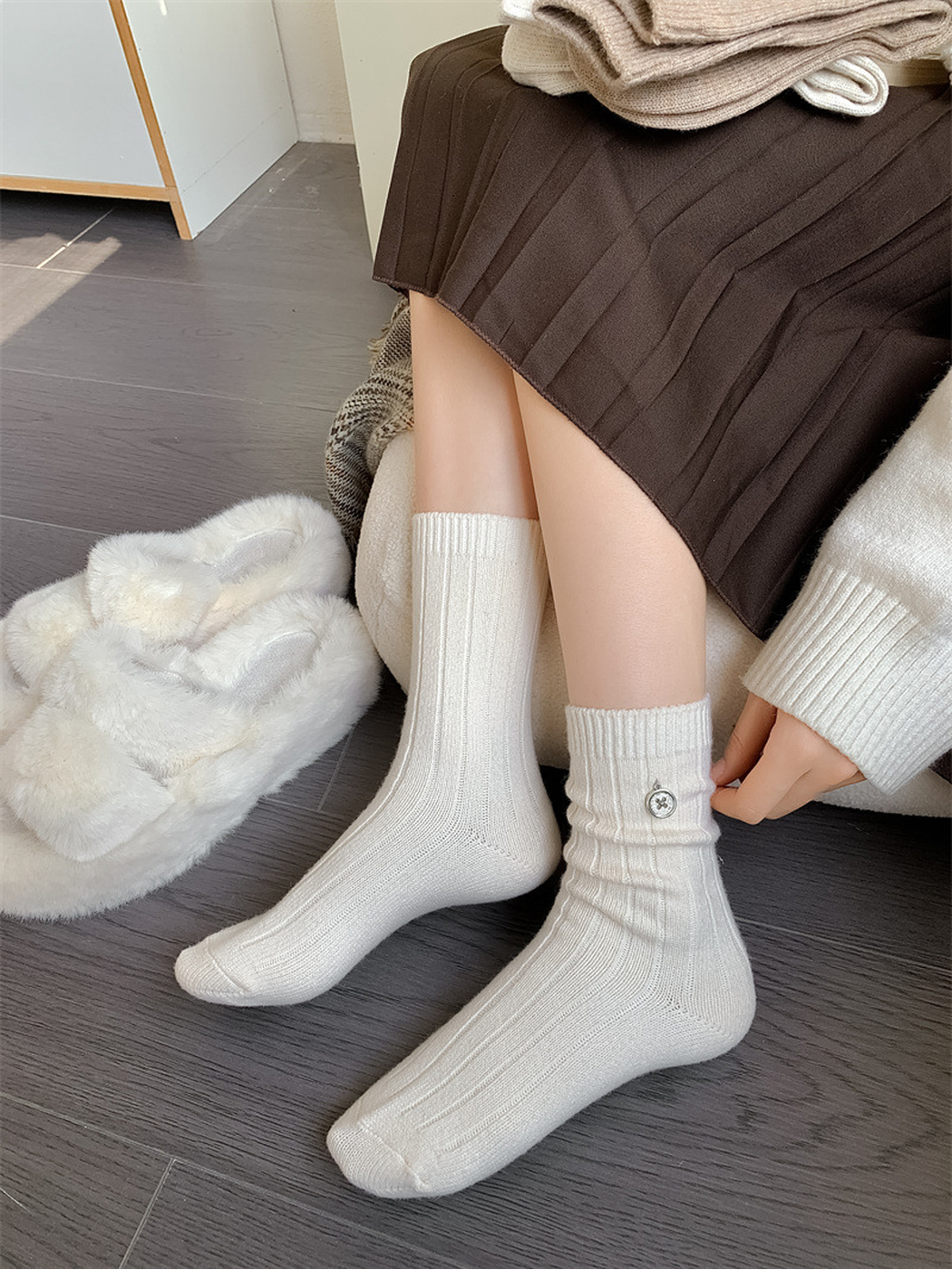Ivory ribbed crew socks worn with a dark pleated skirt