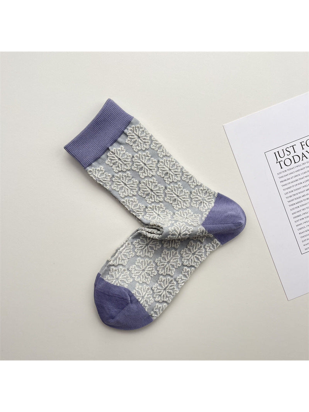 Light gray crew socks with raised white snowflake motifs and lavender trim