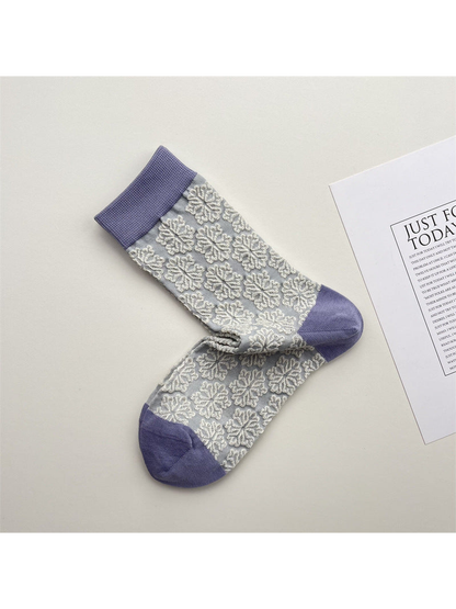 Light gray crew socks with raised white snowflake motifs and lavender trim