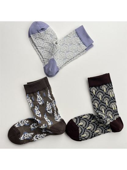 Three patterned crew sock designs arranged in a triangular flat lay