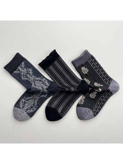 Three dark gray crew sock patterns arranged on a light background