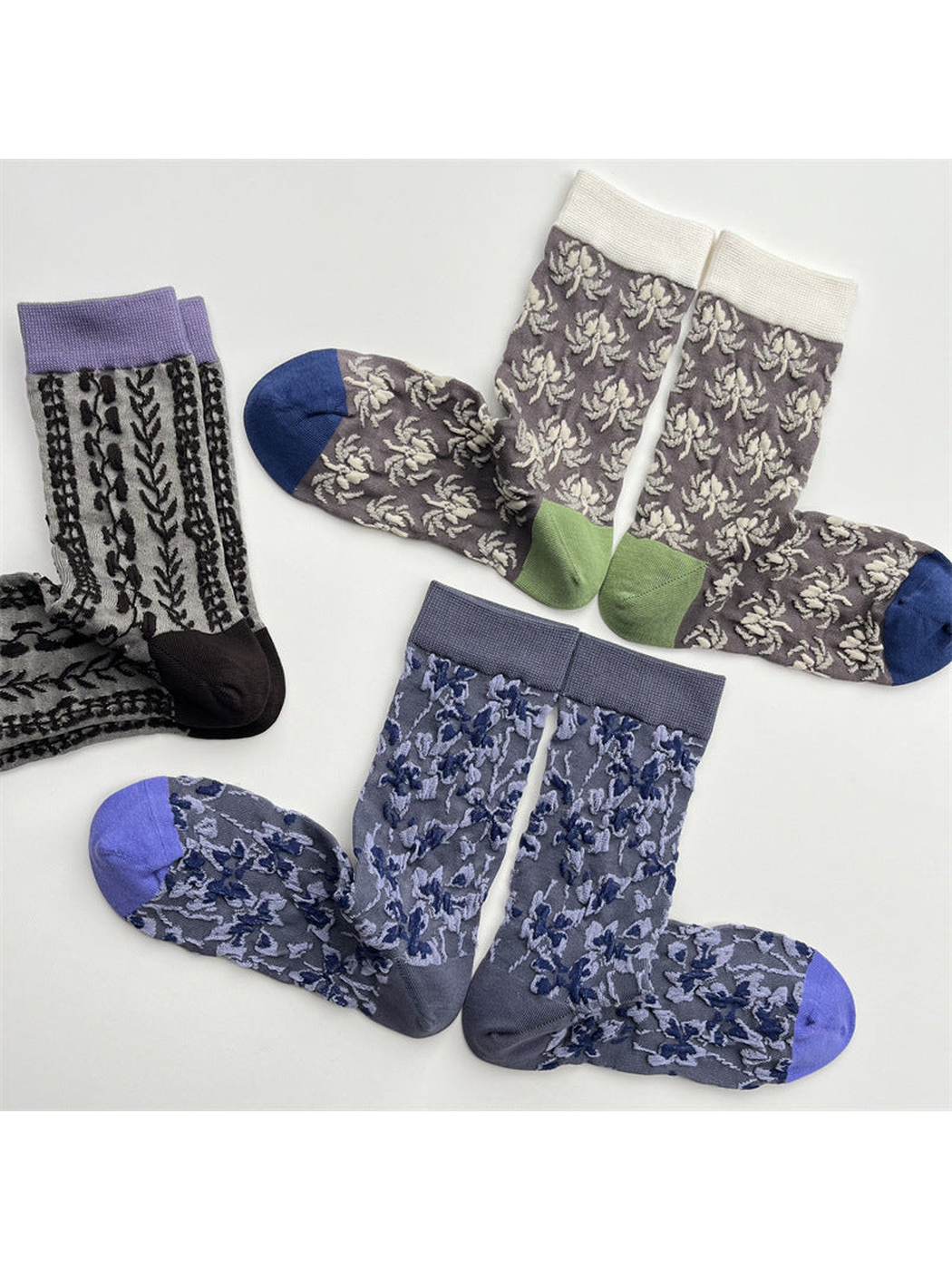 Three patterned crew sock styles in a close flat lay showing contrasting cuffs and toes