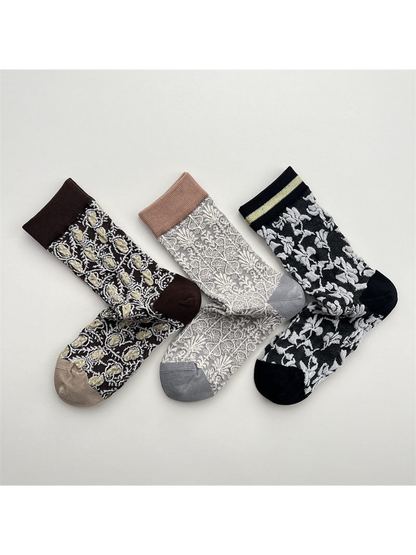 Dark brown, light gray and black patterned crew socks displayed together