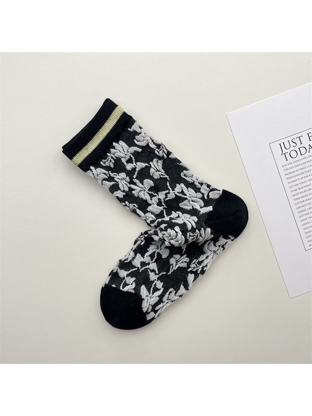 Black crew socks with pale gray floral vines and striped cuffs
