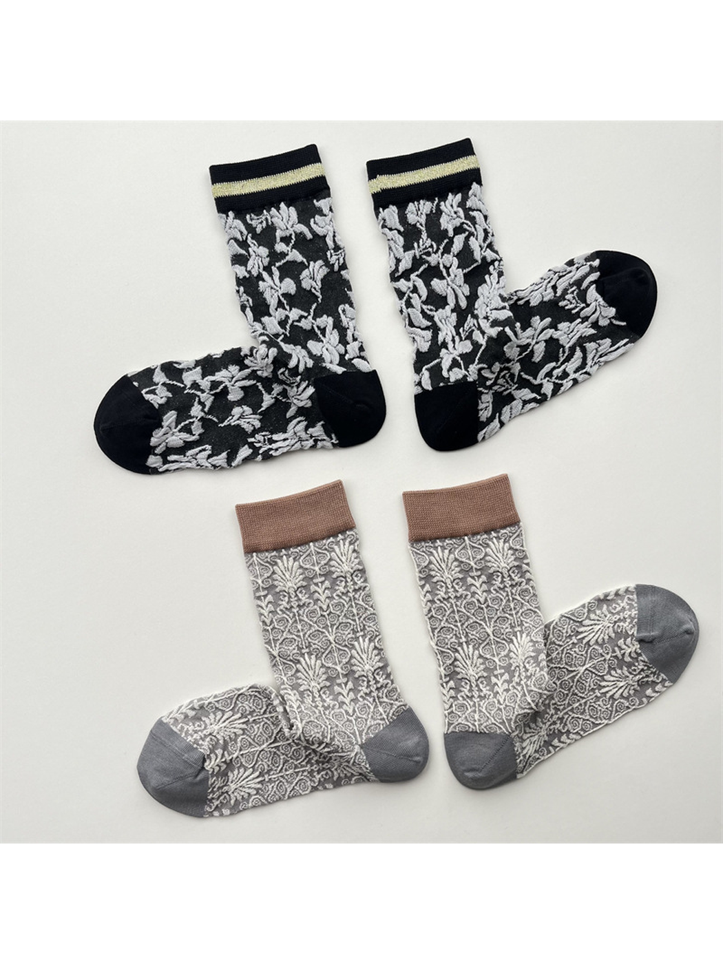 Black floral and light gray ornamental crew socks arranged in pairs