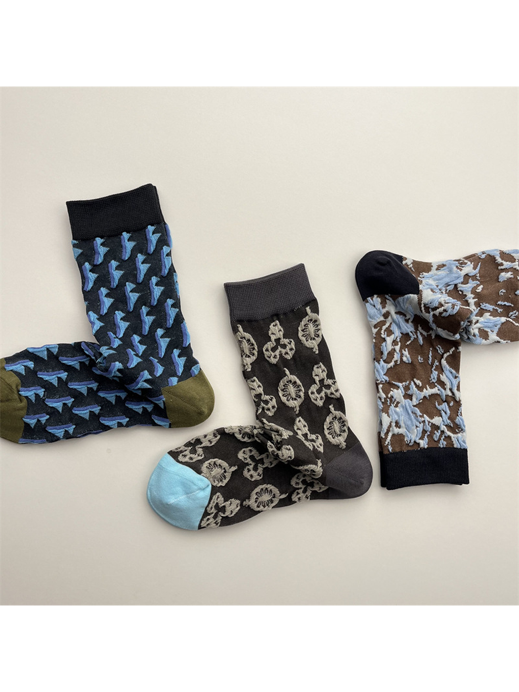 Three patterned crew sock designs arranged across a neutral background