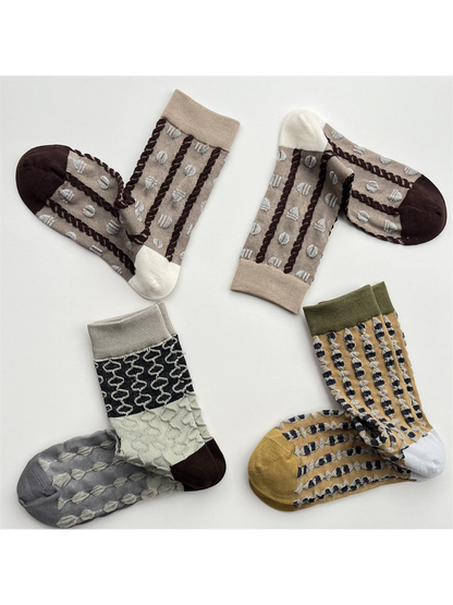 Three pairs of textured geometric crew socks in mustard, khaki and color-block designs
