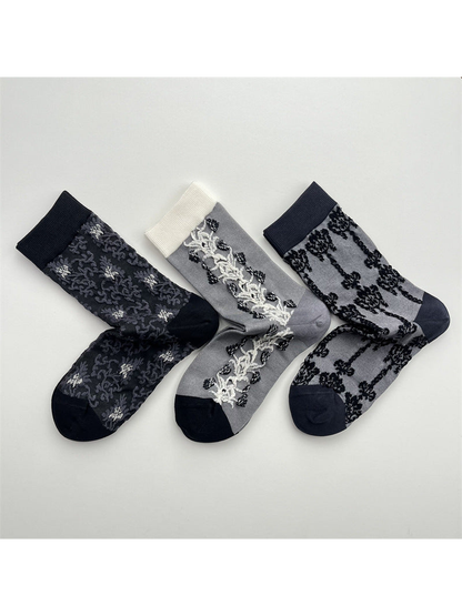 Three gray patterned crew sock designs arranged together