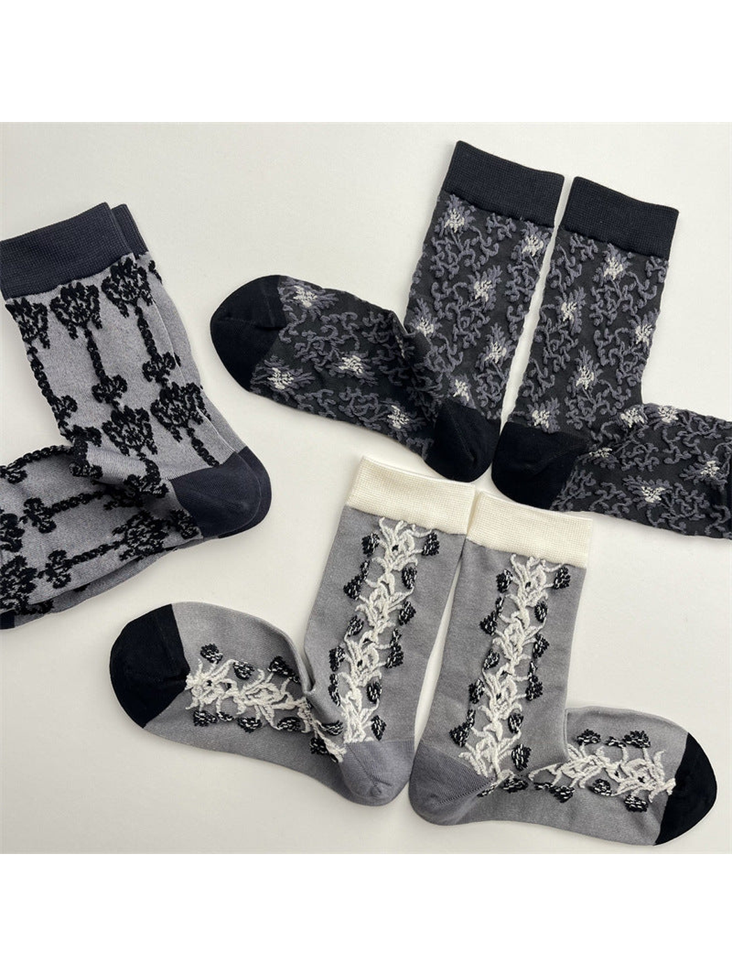 Three gray patterned crew sock designs in an overlapping flat lay