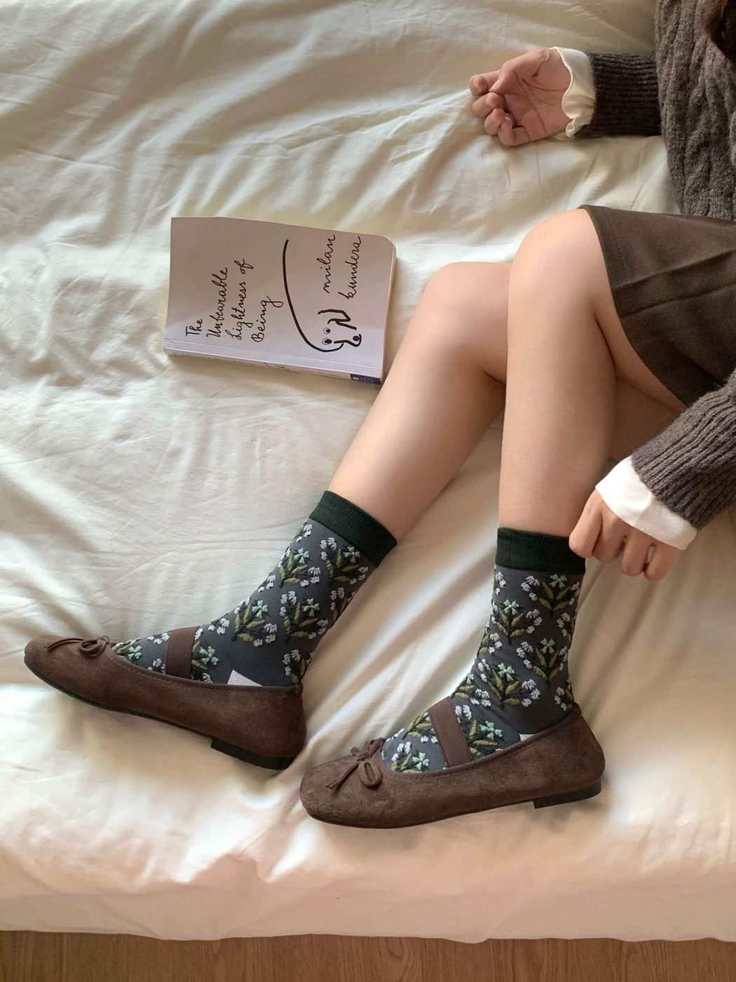 Floral crew socks styled with brown flats while seated on a bed
