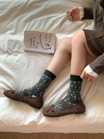 Floral crew socks styled with brown flats while seated on a bed