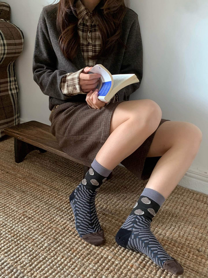 Black and gray patterned crew socks worn while seated indoors