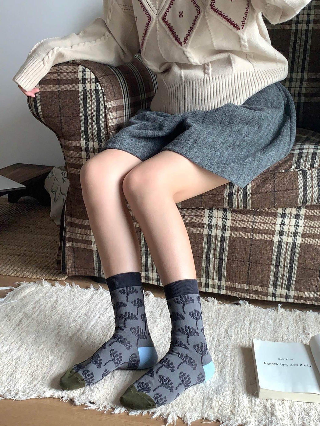 Gray tree-pattern crew socks worn in a seated indoor setting