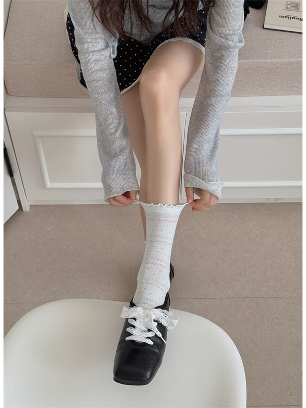 Ivory ruffled crew sock being pulled into place above a black shoe