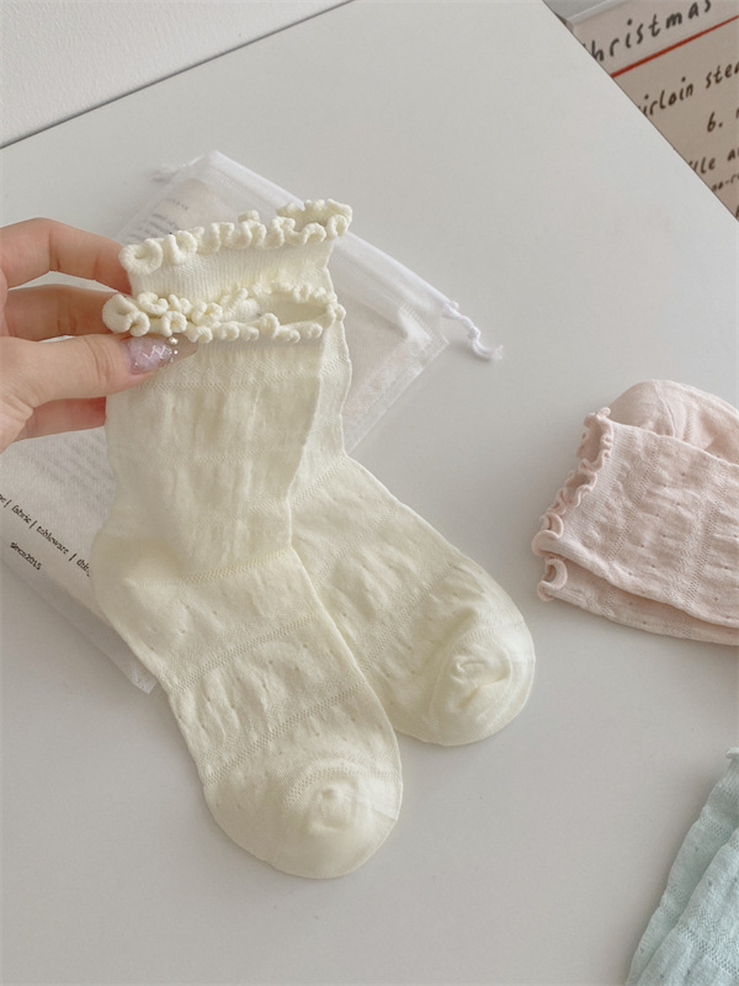 Ivory sock pair with pink and mint ruffled crew socks displayed nearby