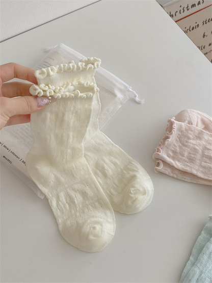 Ivory sock pair with pink and mint ruffled crew socks displayed nearby