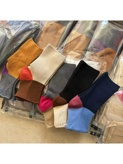 Five color-block open-toe sock designs arranged in a flat lay