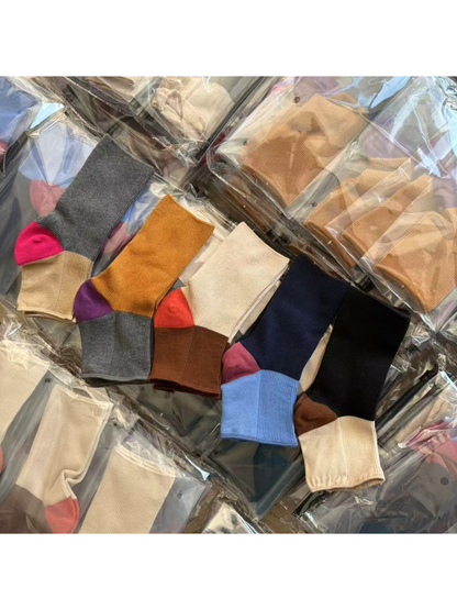 Five color-block open-toe sock designs arranged across packaged stock