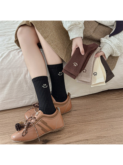 Black ribbed smiley crew socks styled with brown shoes and the color assortment held nearby