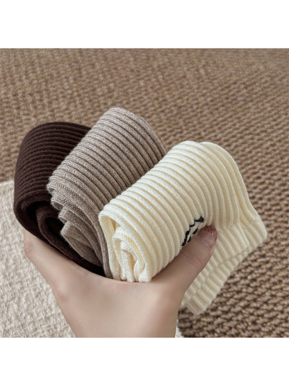 Folded brown, greige and ivory ribbed socks showing the flexible shaft construction