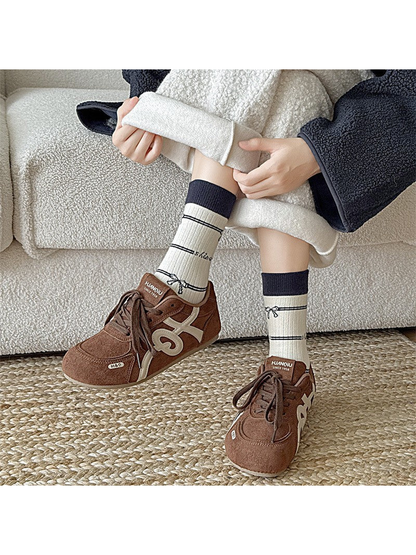 Ivory bow-pattern crew socks styled with brown sneakers