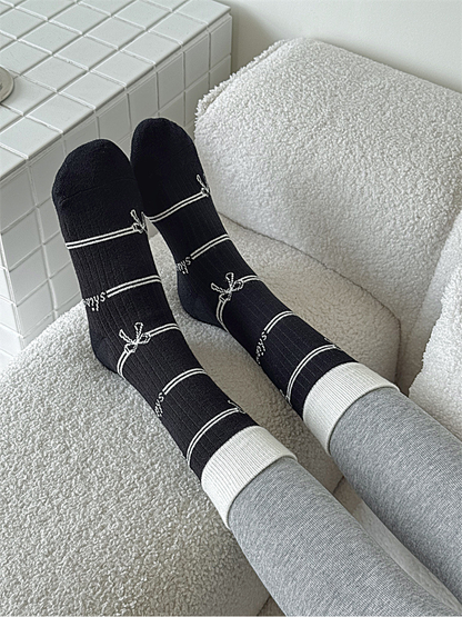 Black bow-pattern crew socks worn in a seated close-up