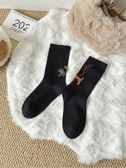Black crew socks with dog-walking motif, full pair view