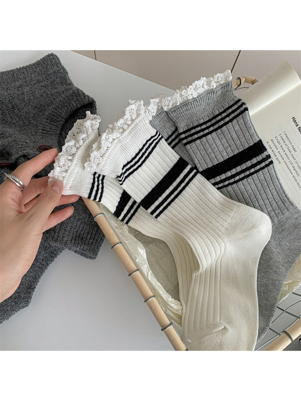 White and light gray ribbed socks displayed close up with striped lace-trimmed cuffs
