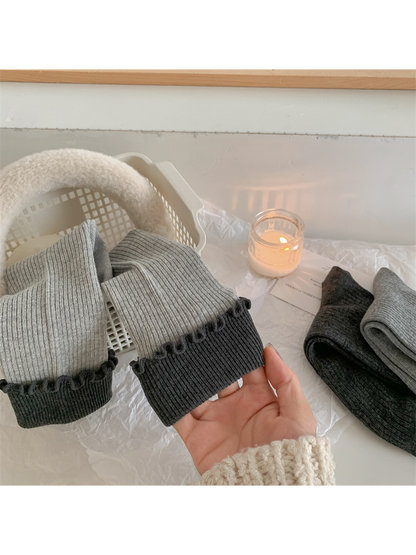 Close-up of light gray ribbed socks with contrasting dark ruffle cuffs